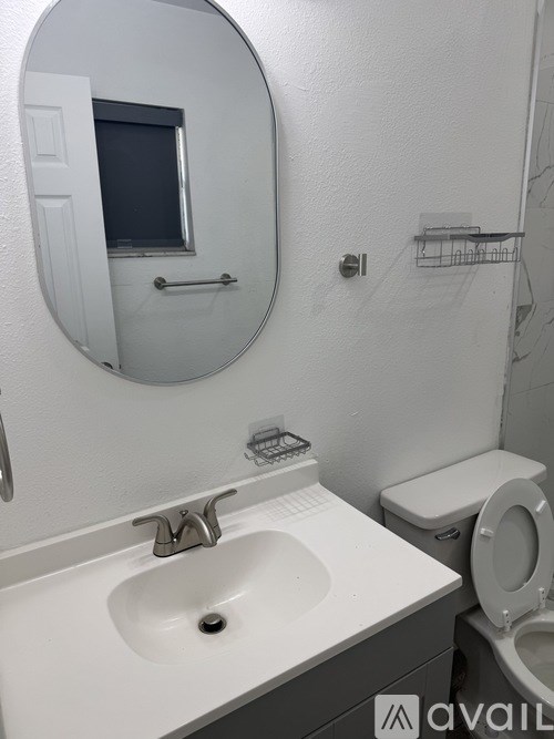 A bathroom with a toilet, sink, and mirror.