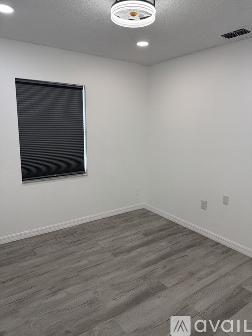 A room with a grey floor and a window with blinds.