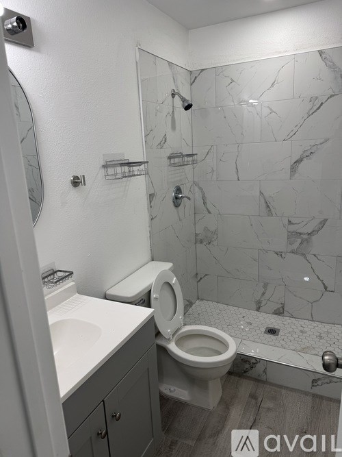 A bathroom with a toilet, sink, and marble tiles.