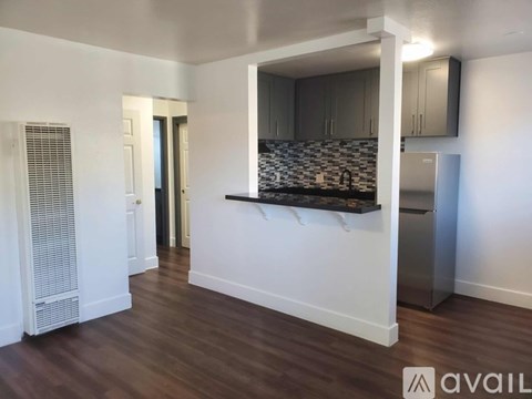 A kitchen area with a stainless steel refrigerator and a countertop with a backsplash.