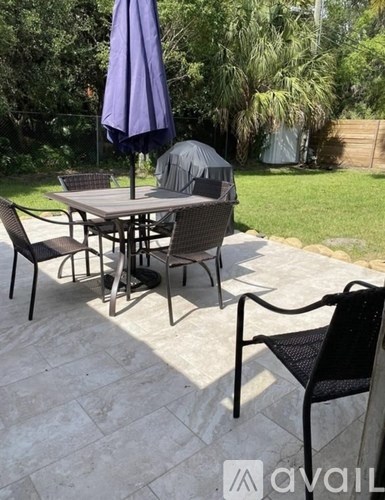 A patio with a table and chairs under a purple umbrella.
