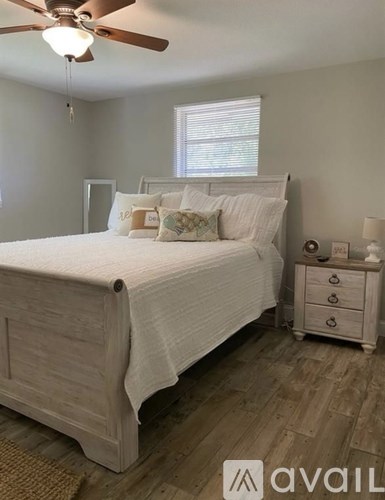 A bedroom with a bed, nightstand, and a ceiling fan.