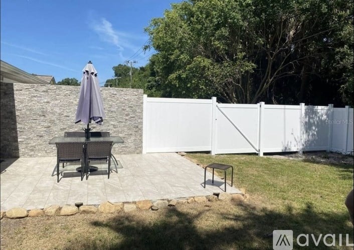 A patio with a table and chairs and a white fence.