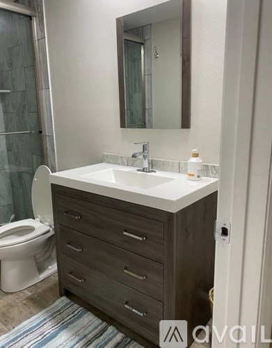 A bathroom with a white sink and a brown cabinet.