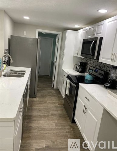 A kitchen with white cabinets and a black countertop.