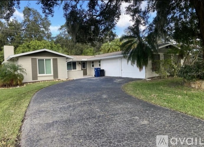 A house with a driveway and a blue trash bin.