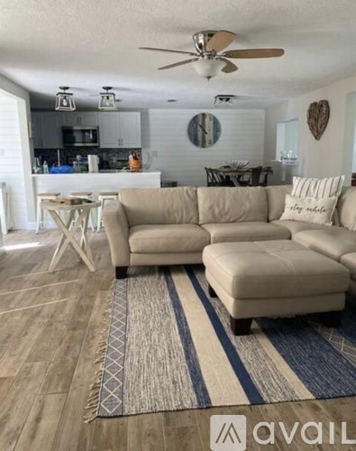 A living room with a beige couch and a rug with a blue stripe.