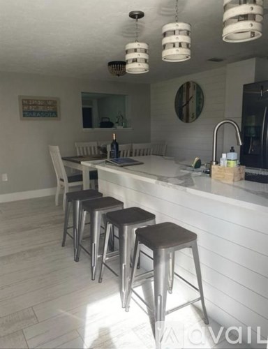 A kitchen with white cabinets and a white island with three stools.