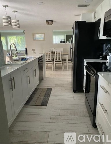A kitchen with black appliances and white cabinets.