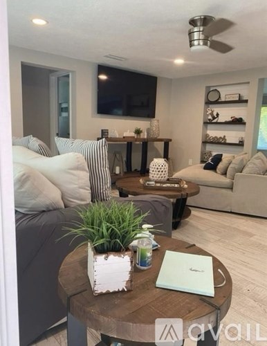 A living room with a grey couch, a wooden coffee table, and a television on the wall.