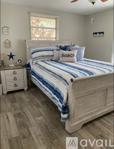 A bedroom with a bed, nightstand, and a window.