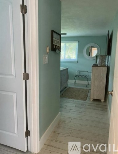 A hallway with a door on the left and a chair and table in the corner.