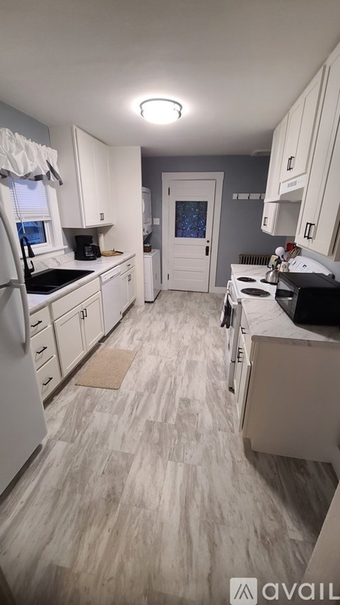 A kitchen with white cabinets and a white fridge.