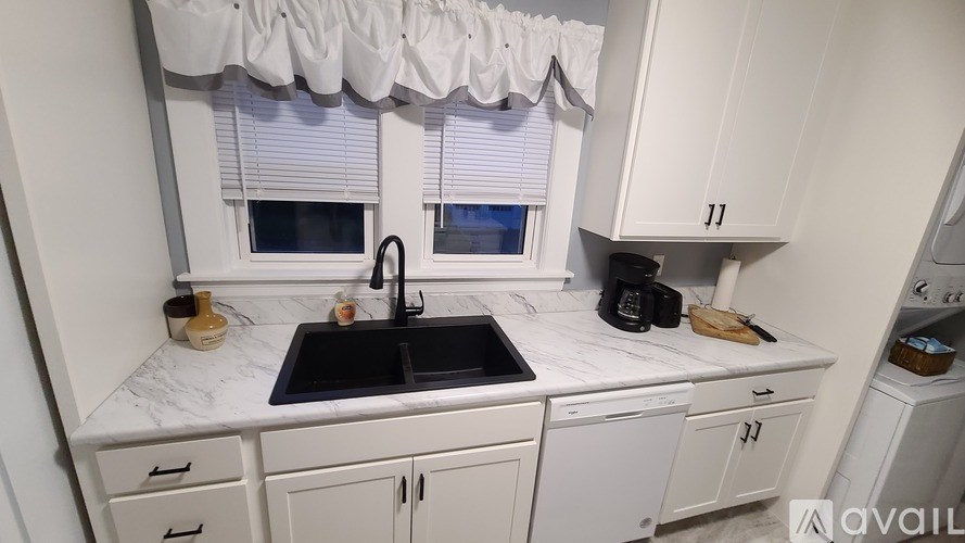 A kitchen with white cabinets and a black sink.