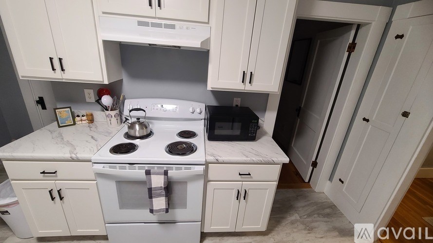 A kitchen with white cabinets and a marble countertop.