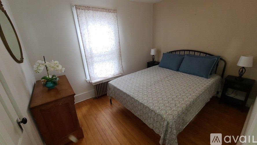 A bedroom with a bed, nightstand, and window.