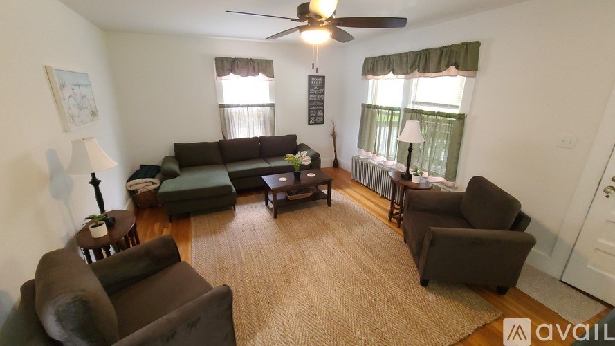 A living room with a couch, chairs, and a rug.