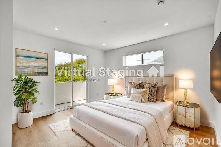 A bedroom with a large bed, a potted plant, and a painting on the wall.