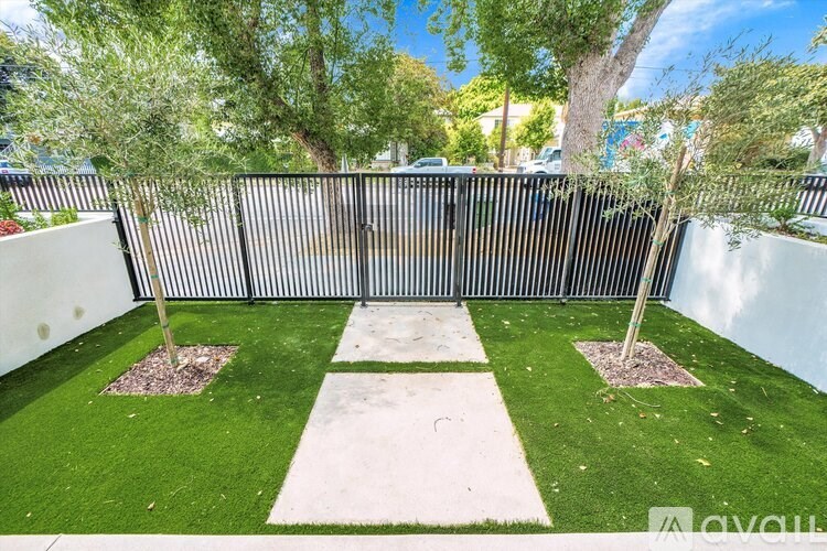A small garden with a white path in the middle and two trees.