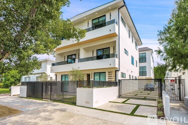 A modern two-story house with a black gate and white walls.