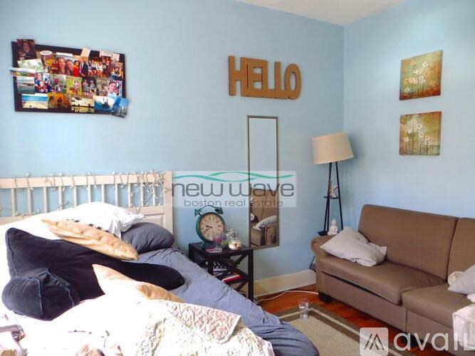 A bedroom with a bed, a couch, and pictures on the wall.