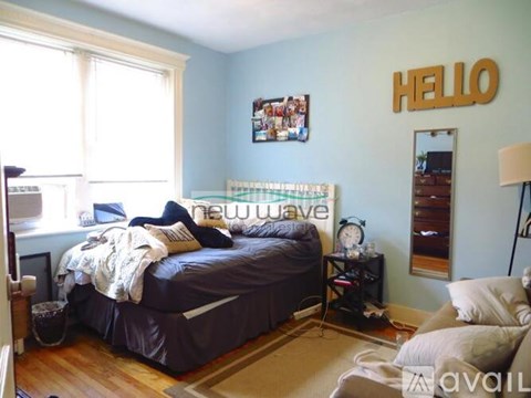 A bedroom with a bed, nightstand, and a wall hanging that says "HELLO".