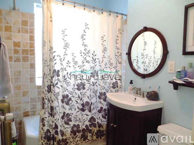 A bathroom with a floral shower curtain and a round mirror.
