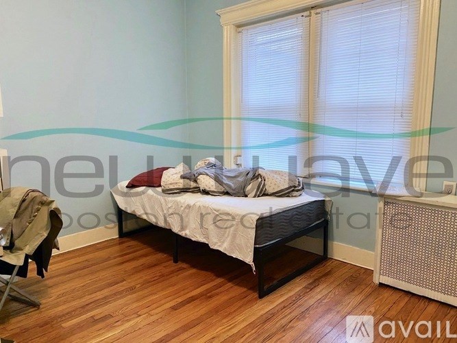 A bedroom with a bed, chair, and window.