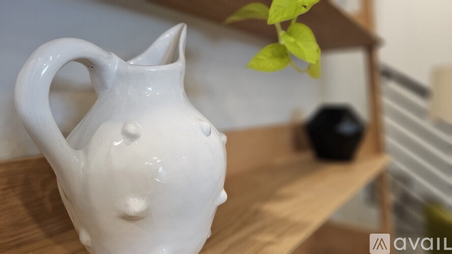 A white ceramic pitcher with a leaf on the side.