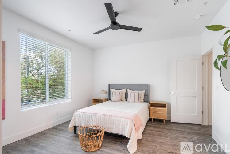 A bedroom with a bed, nightstand, and window with blinds.