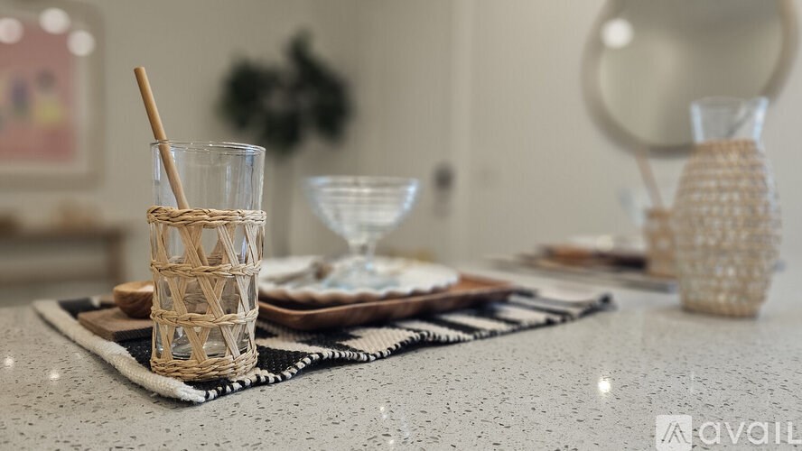 A table setting with a glass, a wicker cup, and a woven basket.