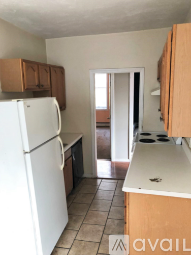 A kitchen with a white refrigerator and wooden cabinets.