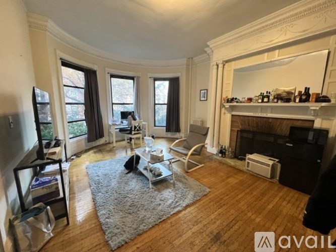 A living room with a fireplace and a grey rug.