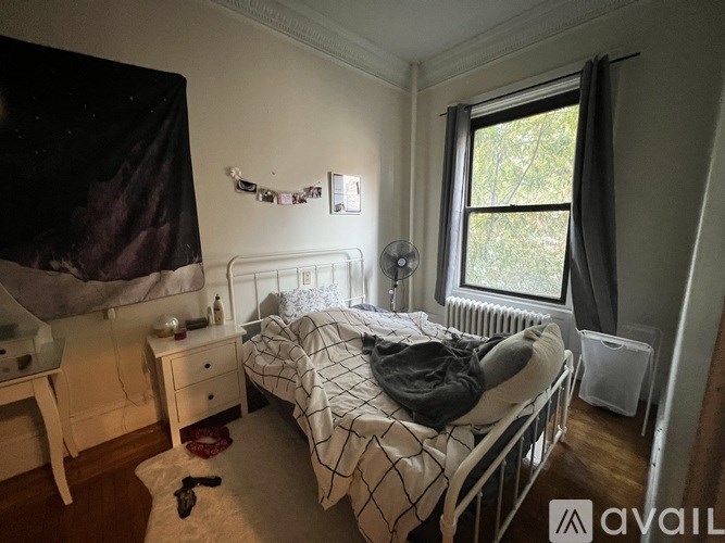 A bedroom with a bed, desk, and window.