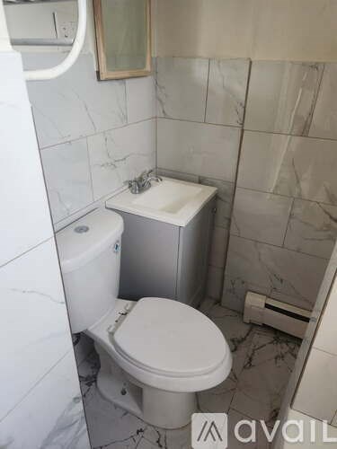 A white toilet in a small bathroom with marble tiles.