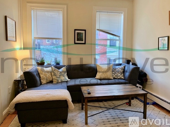 A living room with a black couch and a wooden coffee table.