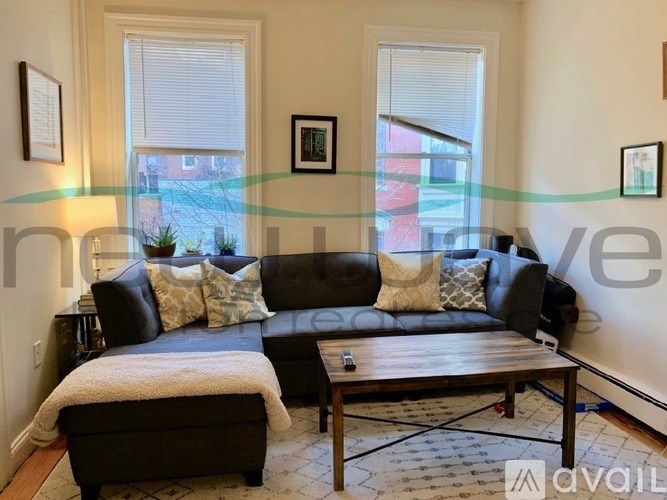 A living room with a black couch and a wooden coffee table.