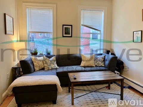 A living room with a black couch and a wooden coffee table.