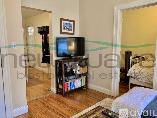 A living room with a television, a bookshelf, and a bed.