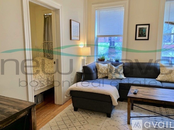 A living room with a black couch, a coffee table, and a rug.