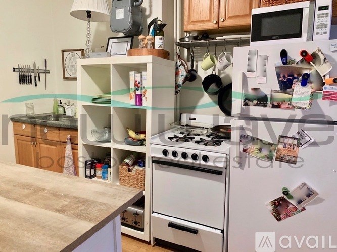 A kitchen with a white fridge covered in magnets and papers.