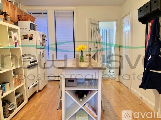 A kitchen with a refrigerator, oven, and a dining table with chairs.