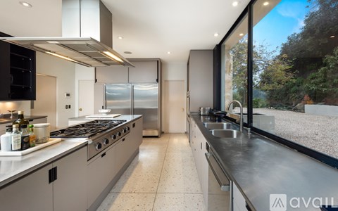 A modern kitchen with a stainless steel refrigerator and a view of the outdoors through the window.