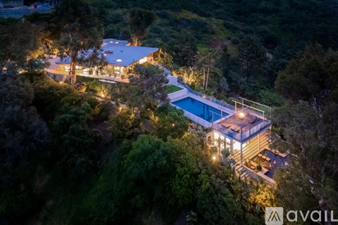 A modern house with a pool surrounded by trees at night.