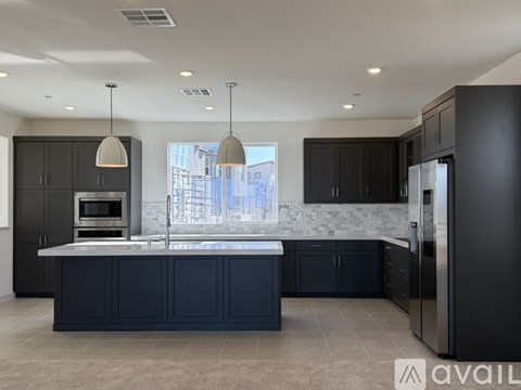 A modern kitchen with dark cabinets and a large island.