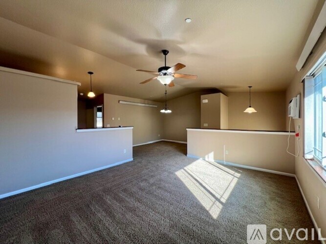 A spacious room with a ceiling fan and carpeted floor.