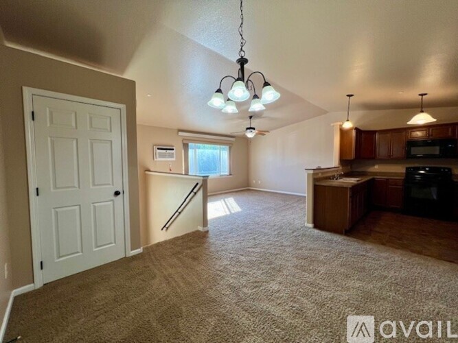 A living room with a carpeted floor and a kitchen area in the background.