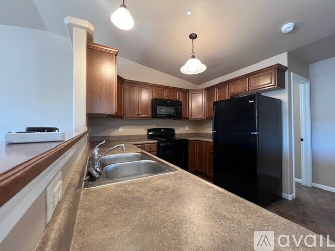 A kitchen with brown cabinets and a black refrigerator.