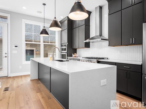 A modern kitchen with black cabinets and a white island.