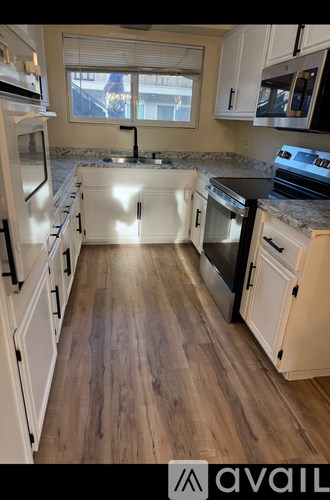 A kitchen with white cabinets and a wooden floor.